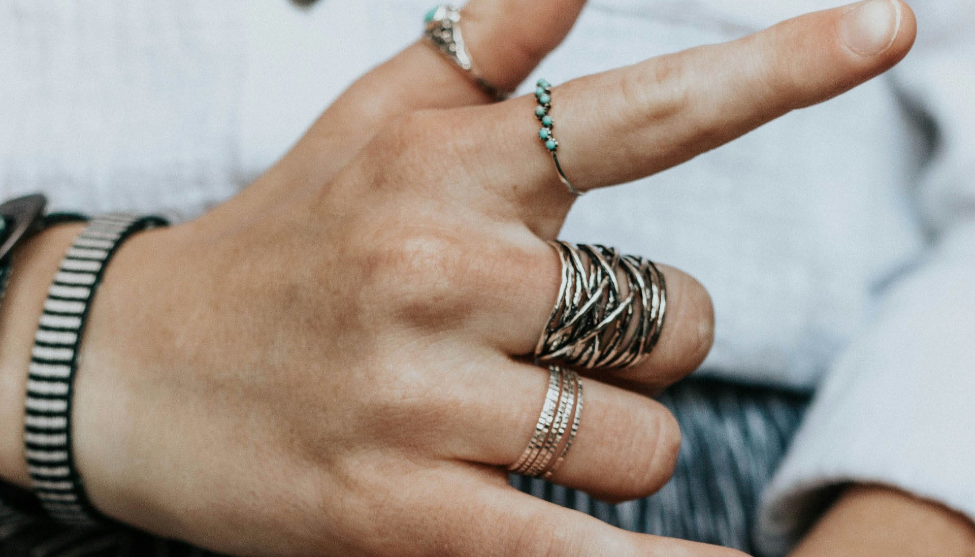 person's hands wearing multiple fashion rings