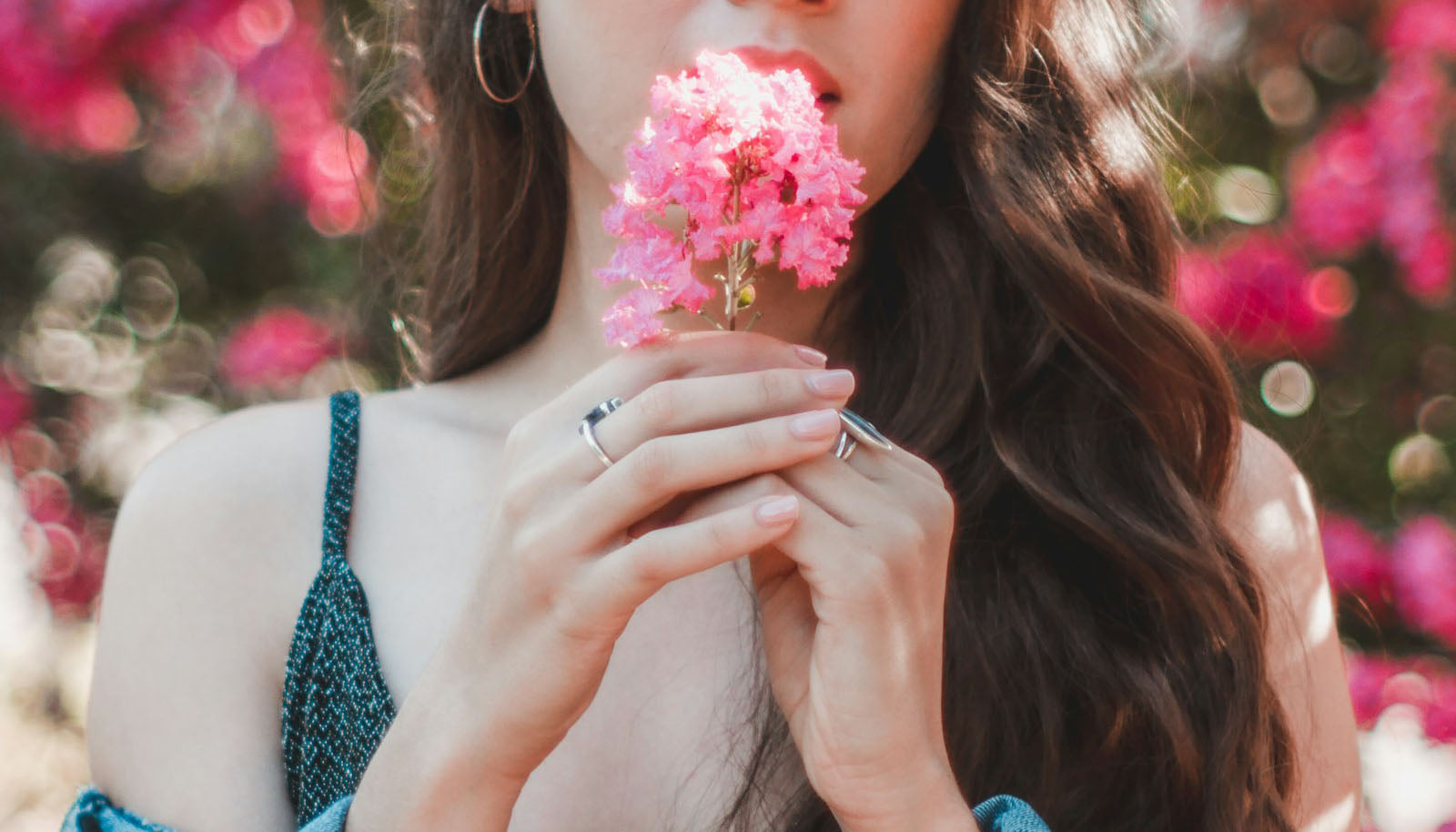 woman holding pink flower and wearing turquoise fashion rings